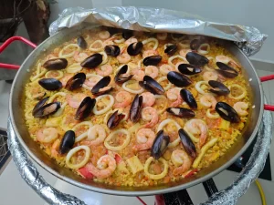 Deliciosa paella de mariscos con camarones, calamares, mejillones y arroz tradicional, preparada con ingredientes frescos y de calidad.